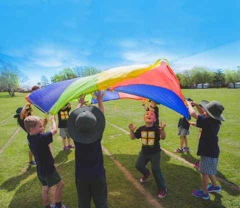 Preschool children using a rainbow parachute