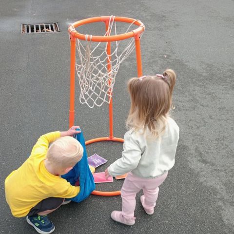Preschool children using a mini basketball hoop